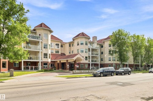 Multi-story building featuring a stucco exterior, red tile roofing, and multiple private balconies with glass railings - #432 6703 172 St Nw, Edmonton, AB 