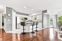 Kitchen featuring white cabinetry, stainless steel appliances, a center island with seating, and tile flooring - 