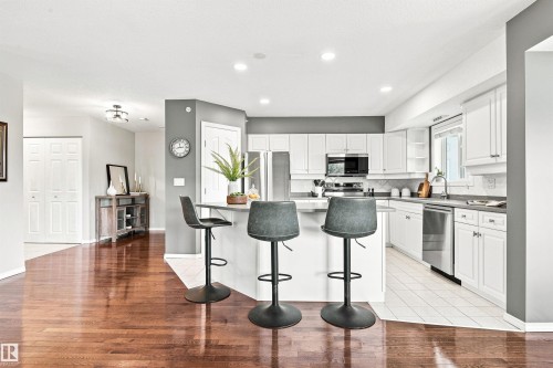 Kitchen featuring white cabinetry, stainless steel appliances, a breakfast bar, and light-toned countertops - #432 6703 172 St Nw, Edmonton, AB 