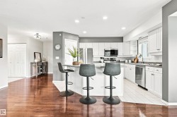 Kitchen featuring white cabinetry, stainless steel appliances, a breakfast bar, and light-toned countertops - 