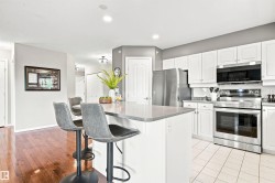 Kitchen featuring white cabinetry, stainless steel appliances, a center island with countertop seating, and tile flooring - 