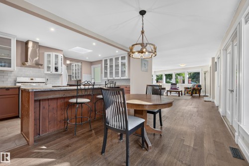 Wood-finish flooring throughout, kitchen island with built-in breakfast bar, white subway tile backsplash, recessed lighting, and kitchen skylight - 11603 72 Avenue Nw, Edmonton, AB 