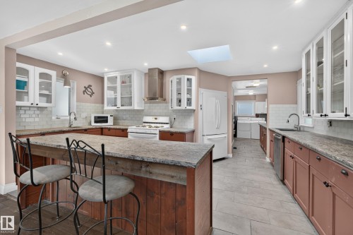 Kitchen featuring a skylight, recessed lighting, white subway tile backsplash, white upper cabinetry, and a peninsula with seating - 11603 72 Avenue Nw, Edmonton, AB 