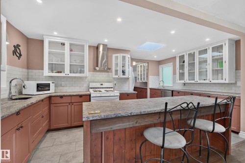 Kitchen featuring an island with stone-finish countertop, recessed lighting, subway tile backsplash, and a skylight - 11603 72 Avenue Nw, Edmonton, AB 