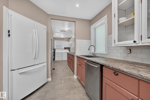 Kitchen featuring a stainless steel dishwasher, a sink with a gooseneck faucet, white subway tile backsplash, and wood-finish countertops - 11603 72 Avenue Nw, Edmonton, AB 