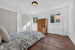 Hardwood flooring, white painted walls, two windows, two bi-fold closets, and a semi-flush mount ceiling light fixture - 