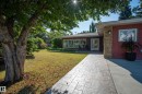 Landscaped front yard with mature trees, stamped concrete walkway, stone facade accents, and a double-door entry - 11603 72 Avenue Nw, Edmonton, AB 