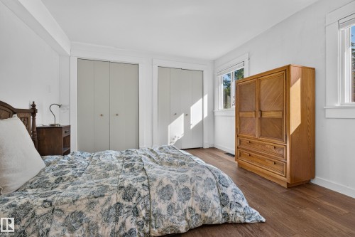 Wood-finish flooring with white trim, two white bi-fold closets, and multiple windows - 11603 72 Avenue Nw, Edmonton, AB 