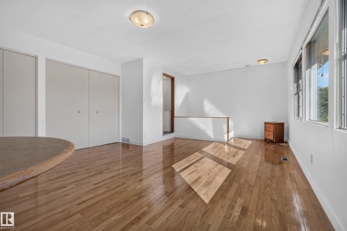 Hardwood flooring, multiple windows, two flush-mount lighting fixtures, and a half-height wall - 11603 72 Avenue Nw, Edmonton, AB 