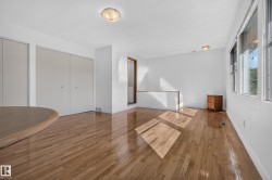 Hardwood flooring, multiple windows, two flush-mount lighting fixtures, and a half-height wall - 