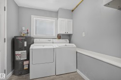 Utility area featuring a window, wall-mounted cabinetry, and tile flooring - 