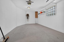 Enclosed garage with concrete flooring, overhead garage door opener, and a glass block window - 
