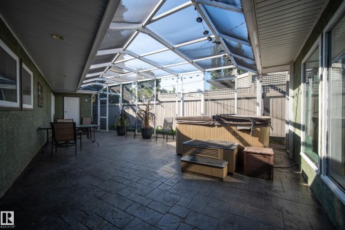 Enclosed patio with a clear panel roof, textured concrete flooring, and a built-in hot tub - 11603 72 Avenue Nw, Edmonton, AB 