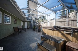 Enclosed patio with a transparent overhead structure, stamped concrete flooring, textured exterior wall, and a built-in outdoor spa - 