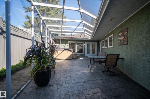 Screened patio featuring a stamped concrete floor, a covered ceiling with skylight panels, and direct access to the interior through double doors and multiple windows - 11603 72 Avenue Nw, Edmonton, AB 