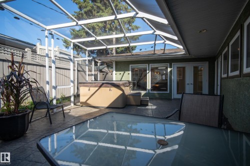 Screened enclosure over a stamped concrete patio, featuring a built-in hot tub - 11603 72 Avenue Nw, Edmonton, AB 