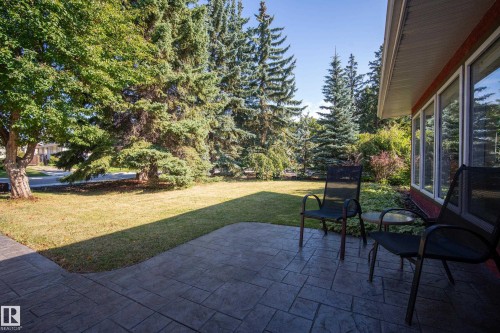 Stamped concrete patio with a manicured lawn, established trees, and large windows - 11603 72 Avenue Nw, Edmonton, AB 