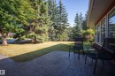 Stamped concrete patio with a manicured lawn, established trees, and large windows - 11603 72 Avenue Nw, Edmonton, AB 
