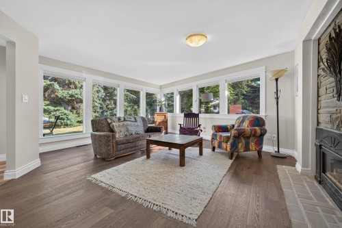 Hardwood-finish flooring, recessed lighting, and a stone-clad fireplace with a tiled hearth create a refined living area - 11603 72 Avenue Nw, Edmonton, AB 