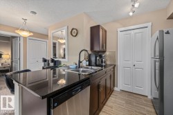 Kitchen featuring dark cabinetry, dark countertops, stainless steel appliances, and a tile backsplash - 