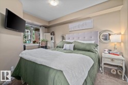 Carpeted bedroom featuring an upholstered headboard, a window with exterior views, and a ceiling-mounted light fixture - 