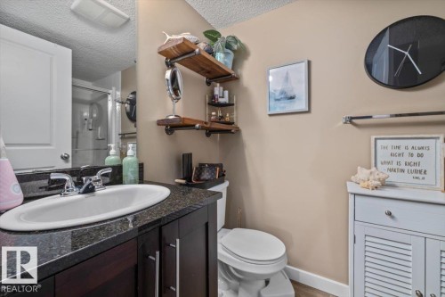 Vanity with a polished chrome faucet, an integrated sink, and dark wood-finish cabinetry - #120 5370 Chappelle Rd Sw, Edmonton, AB 
