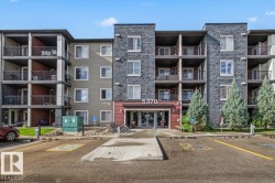 Modern multi-story building featuring stone-look and horizontal panel siding, individual balconies with railings, and a prominent main entrance - 