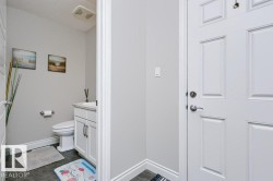 Powder room featuring a white vanity with integrated sink, toilet, and dark tile flooring - 
