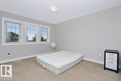 Room featuring three windows with horizontal blinds, light gray wall paint, white baseboards, and neutral-toned carpet flooring - 3496 Weidle Way Sw, Edmonton, AB - Indoor Photo Showing Bedroom
