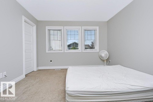 Room featuring three windows with blinds, light gray wall paint, white trim, and neutral carpet flooring - 3496 Weidle Way Sw, Edmonton, AB - Indoor Photo Showing Bedroom