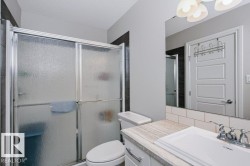 Bathroom featuring a shower with frosted glass enclosure, white subway tile backsplash, light-toned countertop, and a vanity with white cabinetry - 
