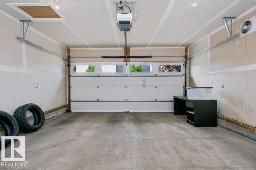 Spacious garage featuring a concrete floor, overhead lighting, and an automatic garage door opener - 3496 Weidle Way Sw, Edmonton, AB - Indoor Photo Showing Garage