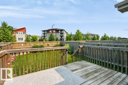 Wood deck with railing and stairs overlooking a fenced yard with green lawn - 