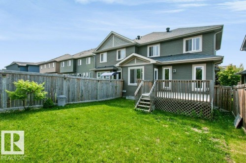 Expansive backyard featuring a manicured lawn, a wooden fence, and a multi-level deck with lattice skirting - 3496 Weidle Way Sw, Edmonton, AB - Outdoor With Deck Patio Veranda