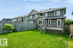 Expansive backyard featuring a manicured lawn, a wooden fence, and a multi-level deck with lattice skirting - 