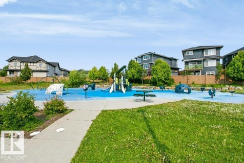 Community park with blue soft-fall surfacing, featuring multiple play structures, spring riders, and a climbing wall - 3496 Weidle Way Sw, Edmonton, AB - Outdoor With In Ground Pool