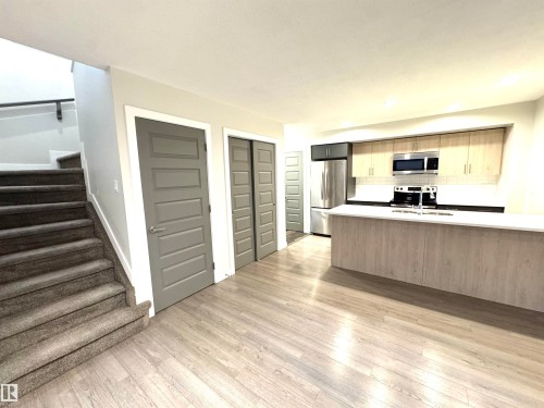 Kitchen featuring stainless steel appliances, light wood-finish cabinetry, and a white countertop island - 12046 89 Street Nw, Edmonton, AB 
