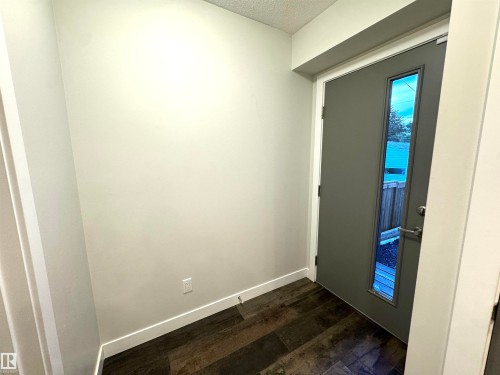 Entryway featuring a contemporary door with a vertical glass insert, dark wood-finish flooring, and light-toned walls - 12046 89 Street Nw, Edmonton, AB 