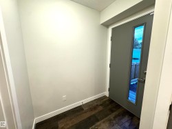 Entryway featuring a contemporary door with a vertical glass insert, dark wood-finish flooring, and light-toned walls - 