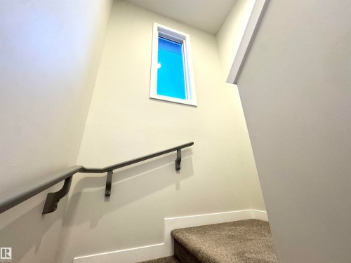 Carpeted staircase with a metal handrail, featuring a high-set window - 12046 89 Street Nw, Edmonton, AB 