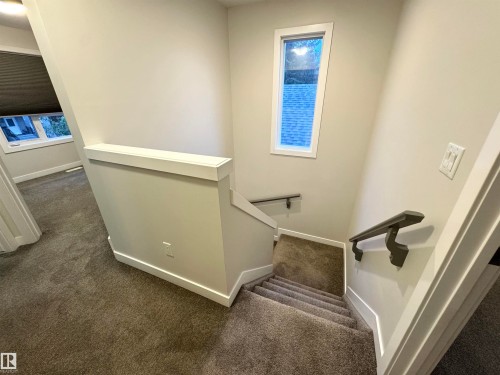 Staircase featuring a window, painted handrails, and neutral-toned carpet flooring - 12046 89 Street Nw, Edmonton, AB 