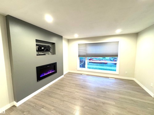 Recessed electric fireplace with a media niche, wood-finish flooring, and recessed ceiling lighting - 12046 89 Street Nw, Edmonton, AB 