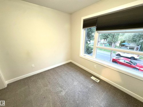 Neutral tone wall finish, white trim, gray carpet, and a large window with blinds - 12046 89 Street Nw, Edmonton, AB 