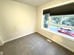 Neutral tone wall finish, white trim, gray carpet, and a large window with blinds - 