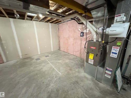 Unfinished basement featuring concrete flooring, exposed ceiling joists, drywall installation, insulation, and a modern furnace - 12046 89 Street Nw, Edmonton, AB 