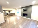 Open-concept living area with wood-finish flooring, a contemporary built-in electric fireplace, recessed lighting, and a kitchen island with a sink - 12046 89 Street Nw, Edmonton, AB 