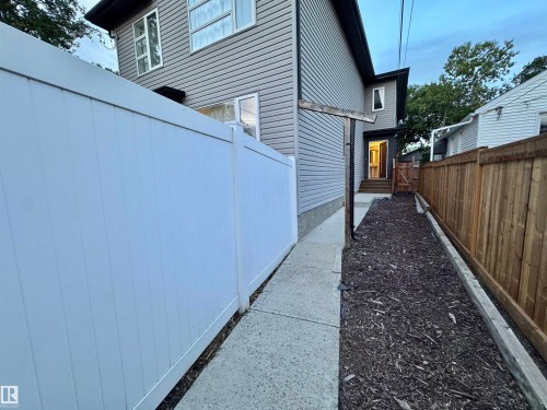 Concrete pathway with a contrasting wood chip landscape bed and wood panel fencing - 12046 89 Street Nw, Edmonton, AB 