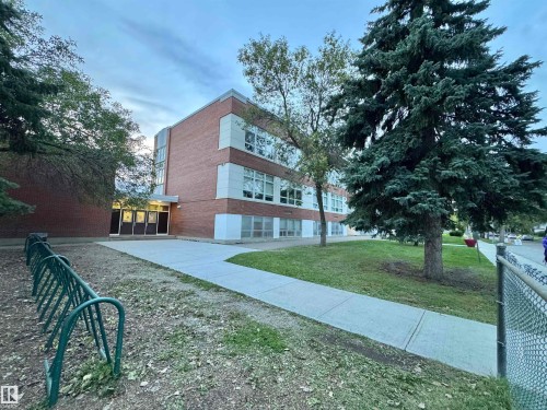 Brick exterior with multiple windows, concrete walkway, and mature trees - 12046 89 Street Nw, Edmonton, AB 