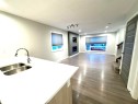 Wood-finish flooring throughout, featuring a kitchen island with an integrated double sink, recessed lighting, and a modern fireplace with a media niche - 12046 89 Street Nw, Edmonton, AB 