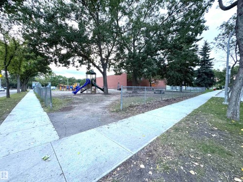 Gated recreational area featuring mature trees and a playground structure with slides - 12046 89 Street Nw, Edmonton, AB 